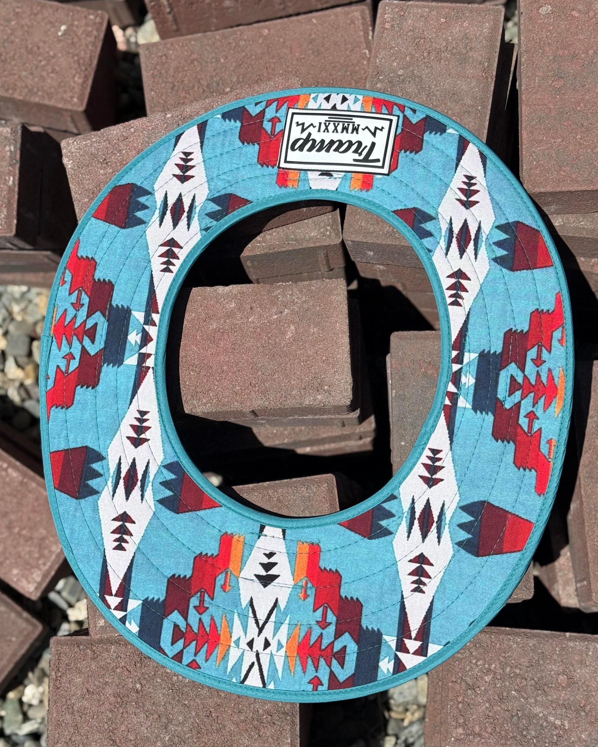 a turquoise sunshade with red, yellow, white and navy accents from tramp life industries on a pile of bricks