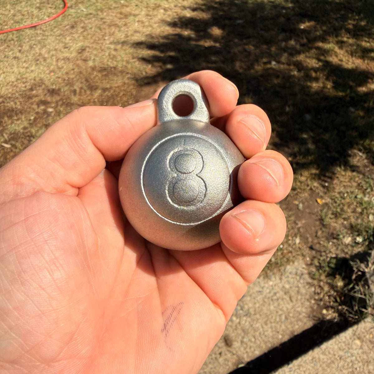  the 8 ball plumb bob from tramp life industries in stainless steel 304 held in a hand to showcase its size