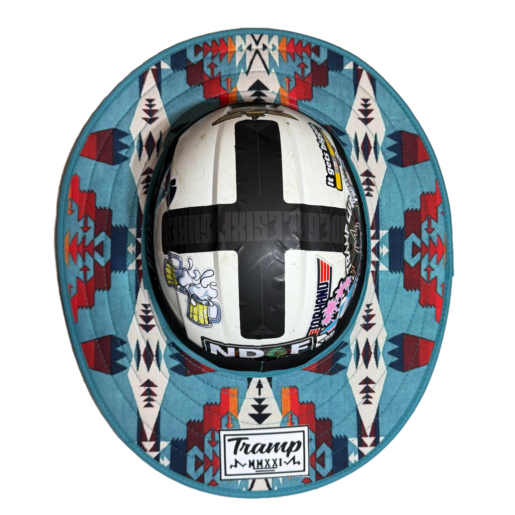 A hardhat with the turquoise sunshade from tramp life industries. it has red, blue, navy, white, and orange geometric design on it