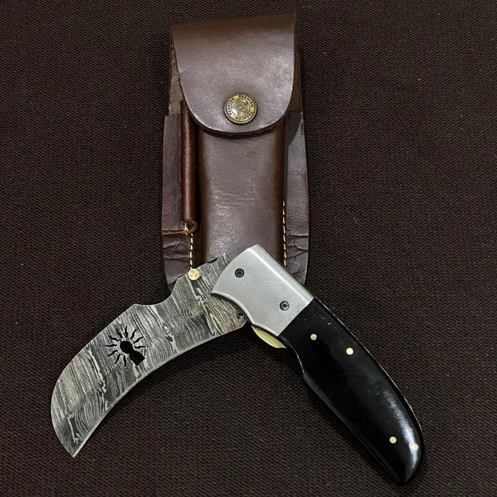 Knife with black handle and damascus steel blade in a leather sheath on a dark background