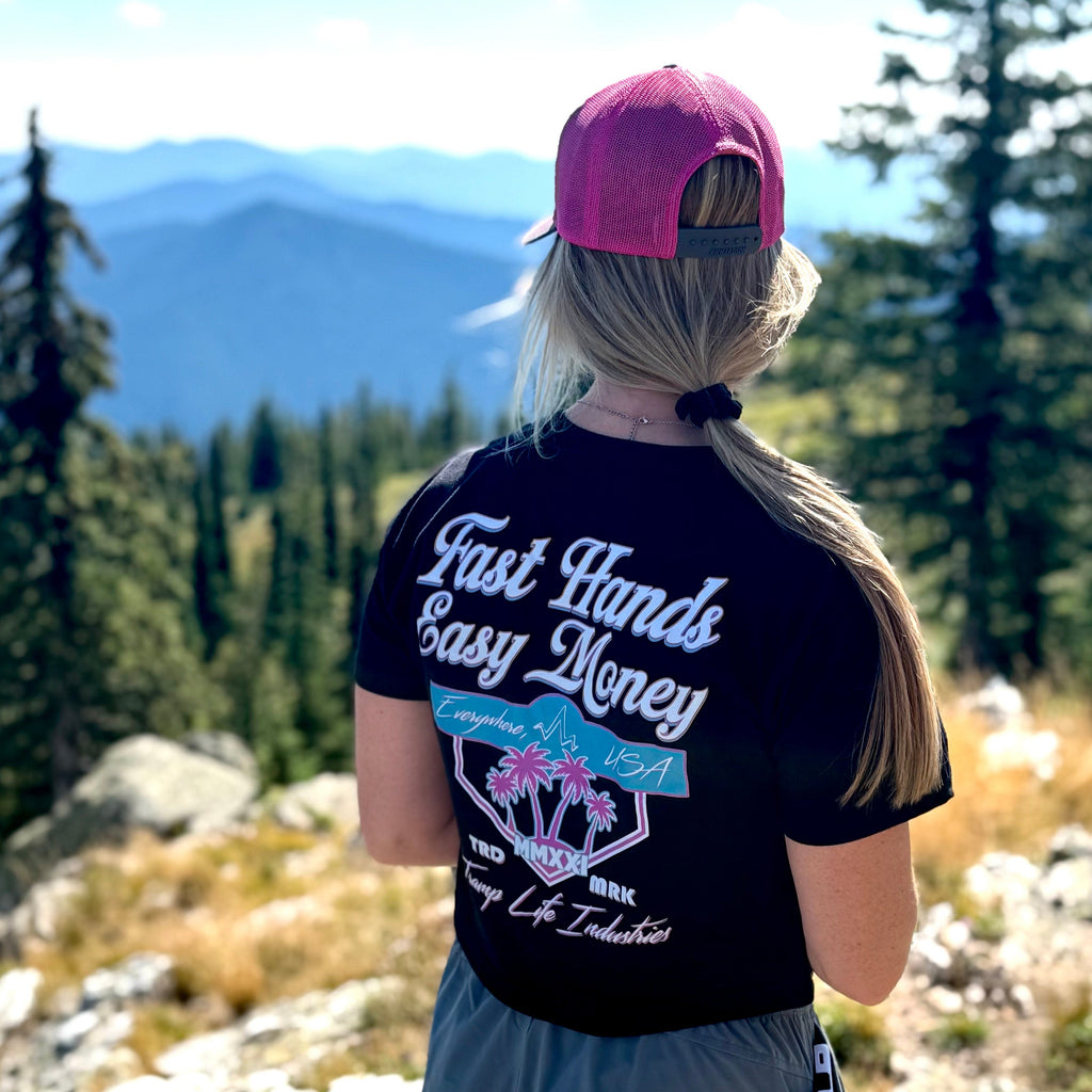 woman wearing a fast hands easy money shirt from tramp life standing on a mountain