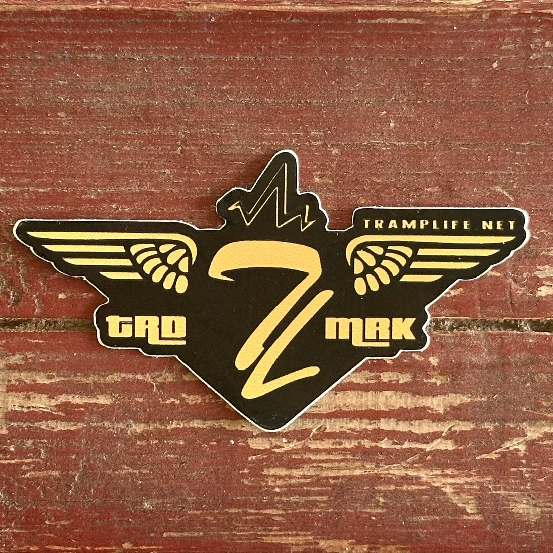   TL from tramp life with gold wings coming off of it