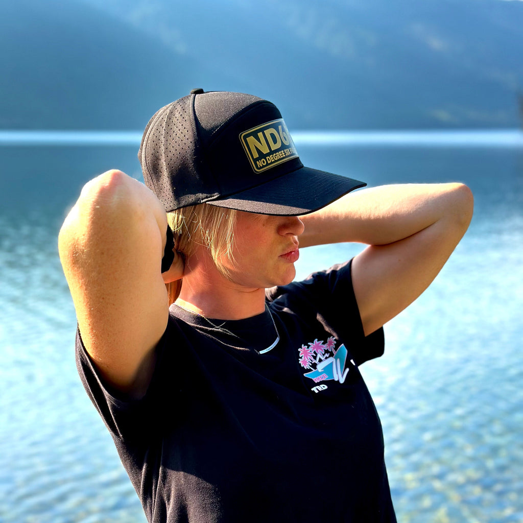 woman wearing a nd6f gold hat from tramp life standing in front of sullivan lake