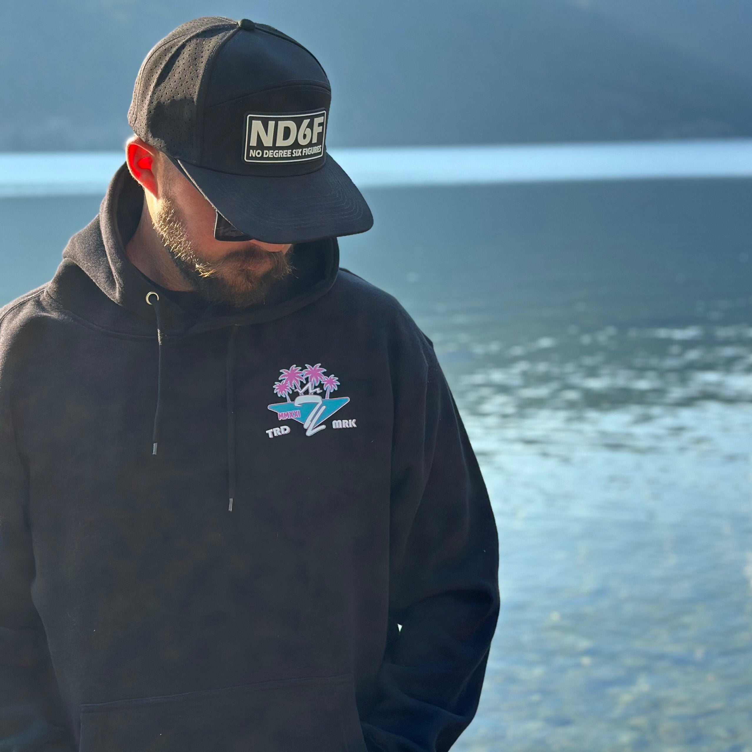 man standing next to water with a hoodie from tramp life