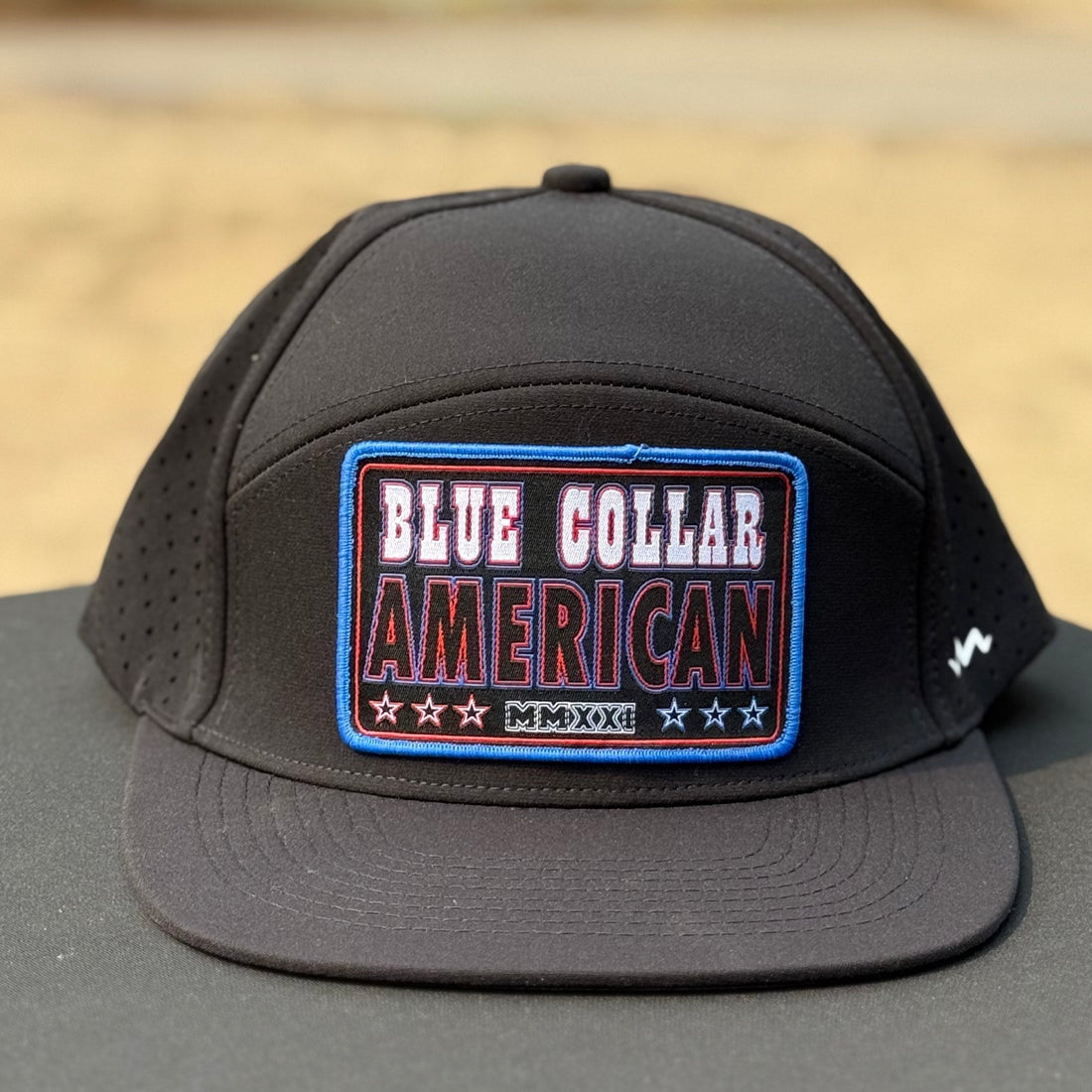 black flat bill hat that says blue collar american with red white and blue colors on a black table