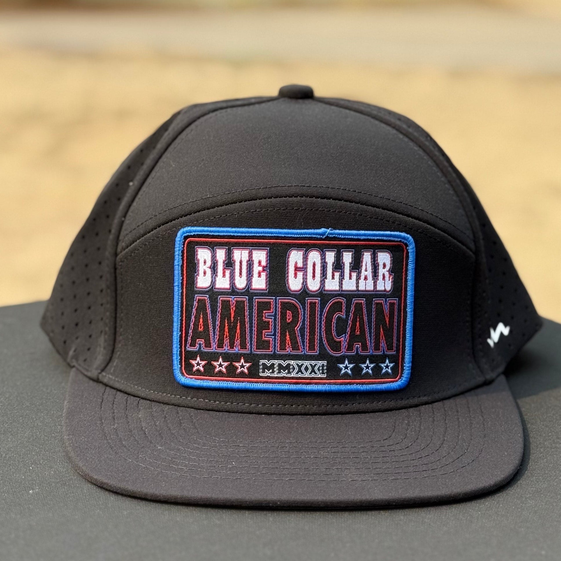 black flat bill hat that says blue collar american with red white and blue colors on a black table