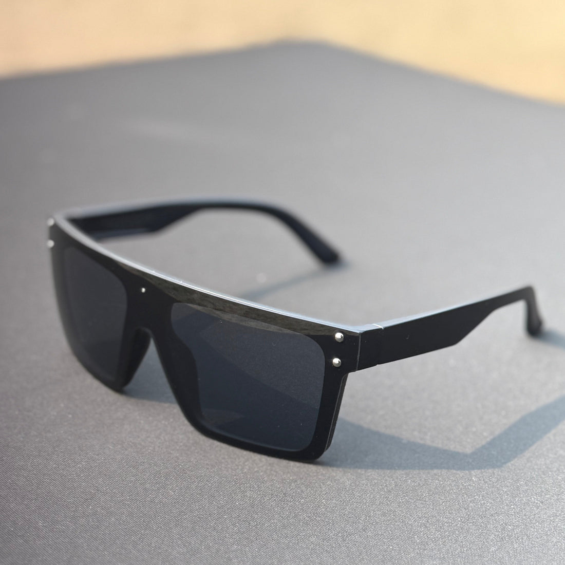 Black sunglasses on a gray surface with a blurred background