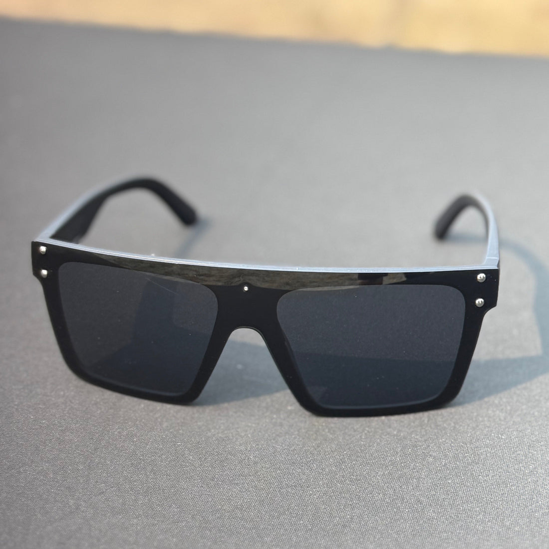Black sunglasses on a gray surface with a blurred background