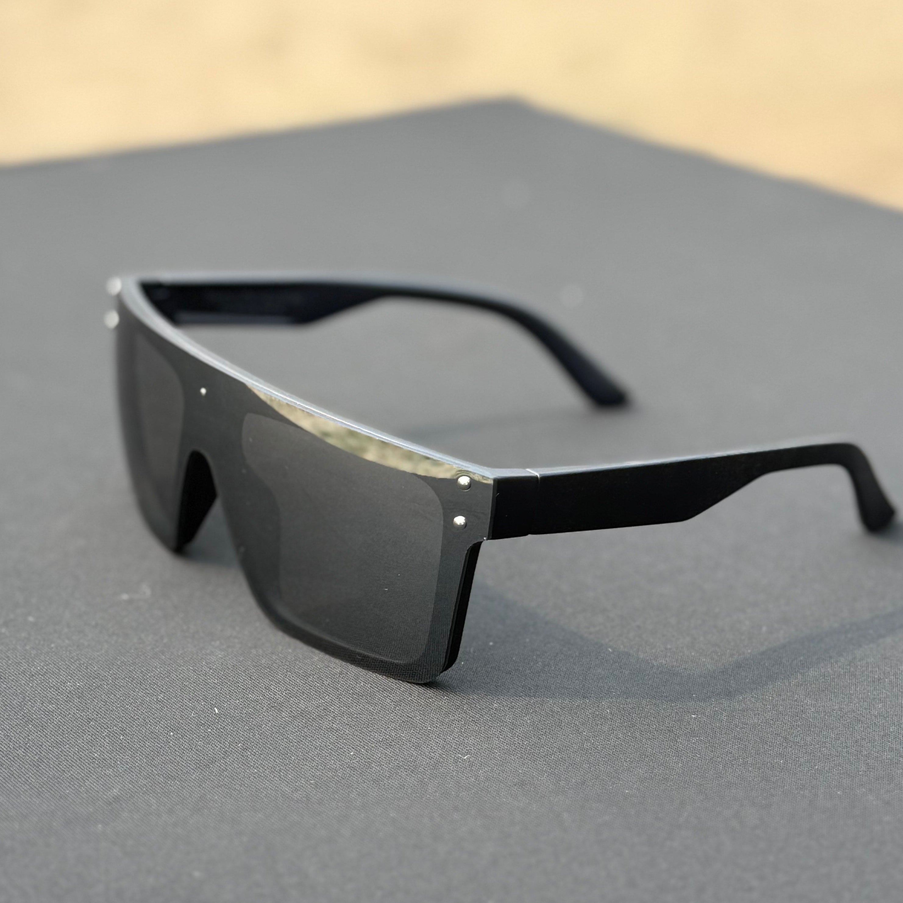 Black sunglasses on a gray surface with a blurred background