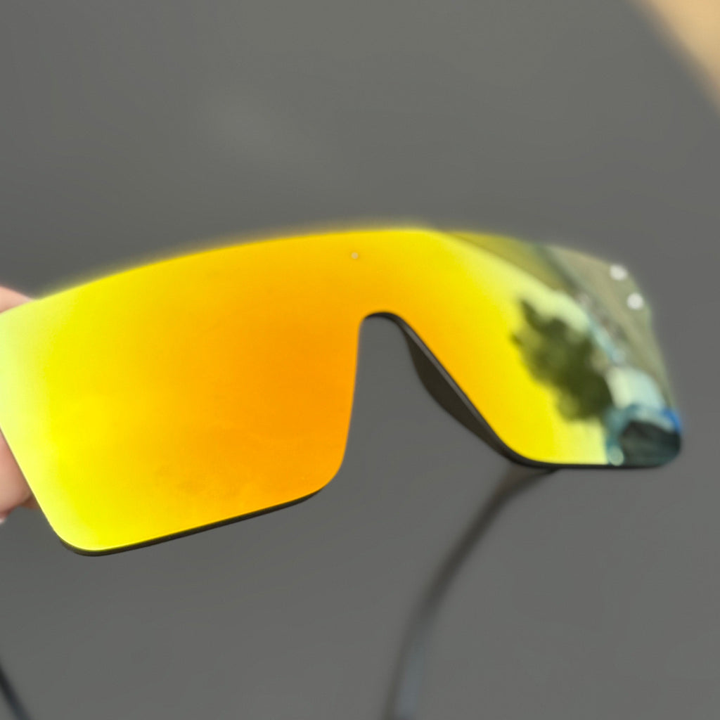 Yellow reflective sunglasses held by a hand with a blurred background