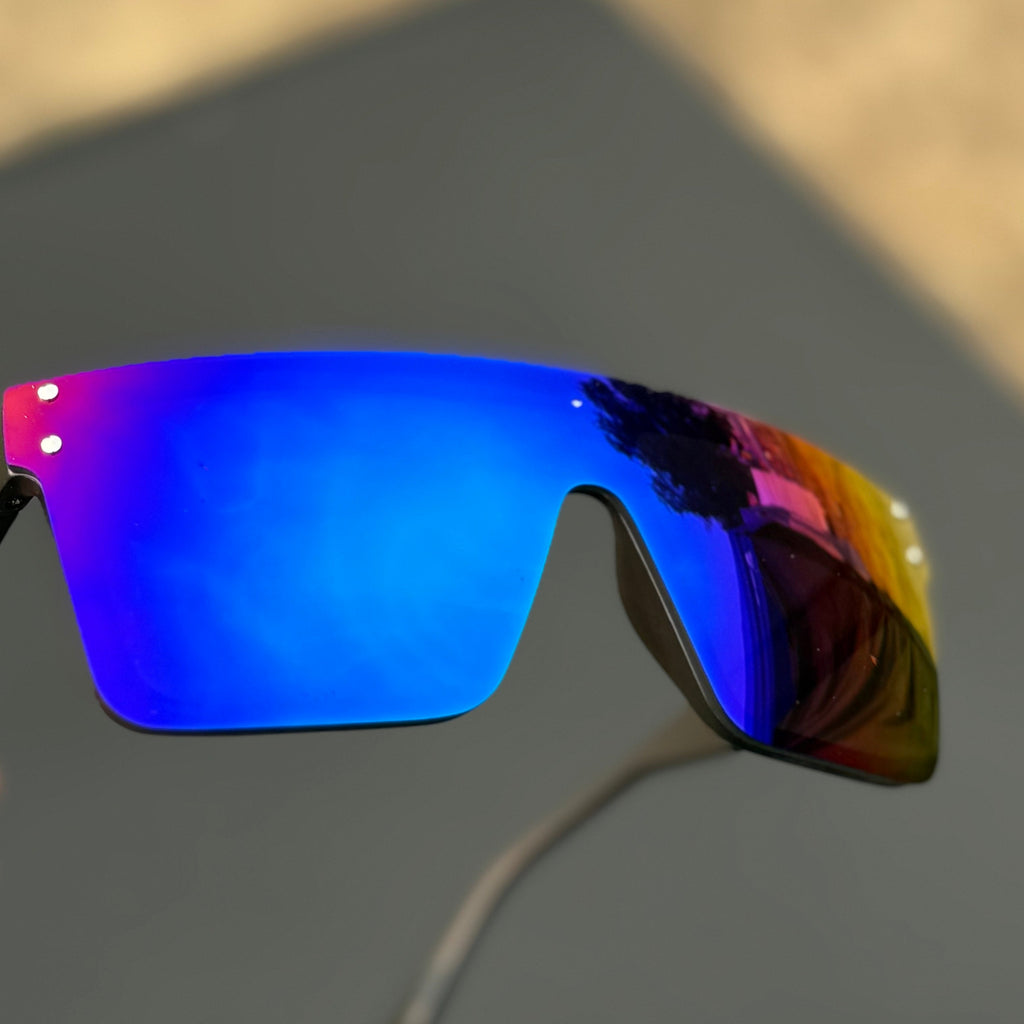 Sunglasses with blue lenses held against a blurred background