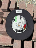 An all-black sunshade from tramp life industries with a PVC patch sewn into it with the words TRAMP on a white hard hat with tramp life stickers