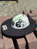 An all-black sunshade from tramp life industries with a PVC patch sewn into it with the words TRAMP on a white hard hat with tramp life stickers