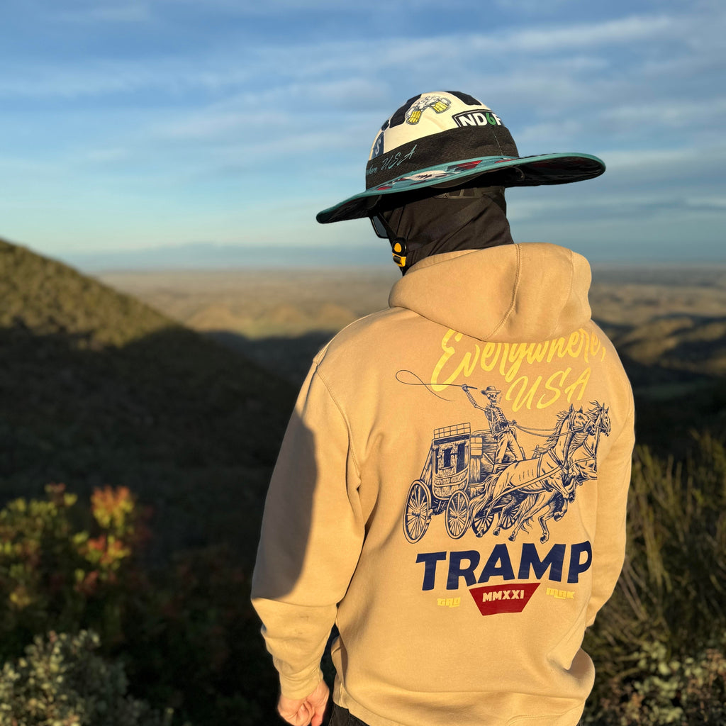 person standing on the side of a cliff wearing a hoodie from tramp life that says TRAMP. depicts a skeleton on a buggy with a whip and 2 horses pulling the buggy.