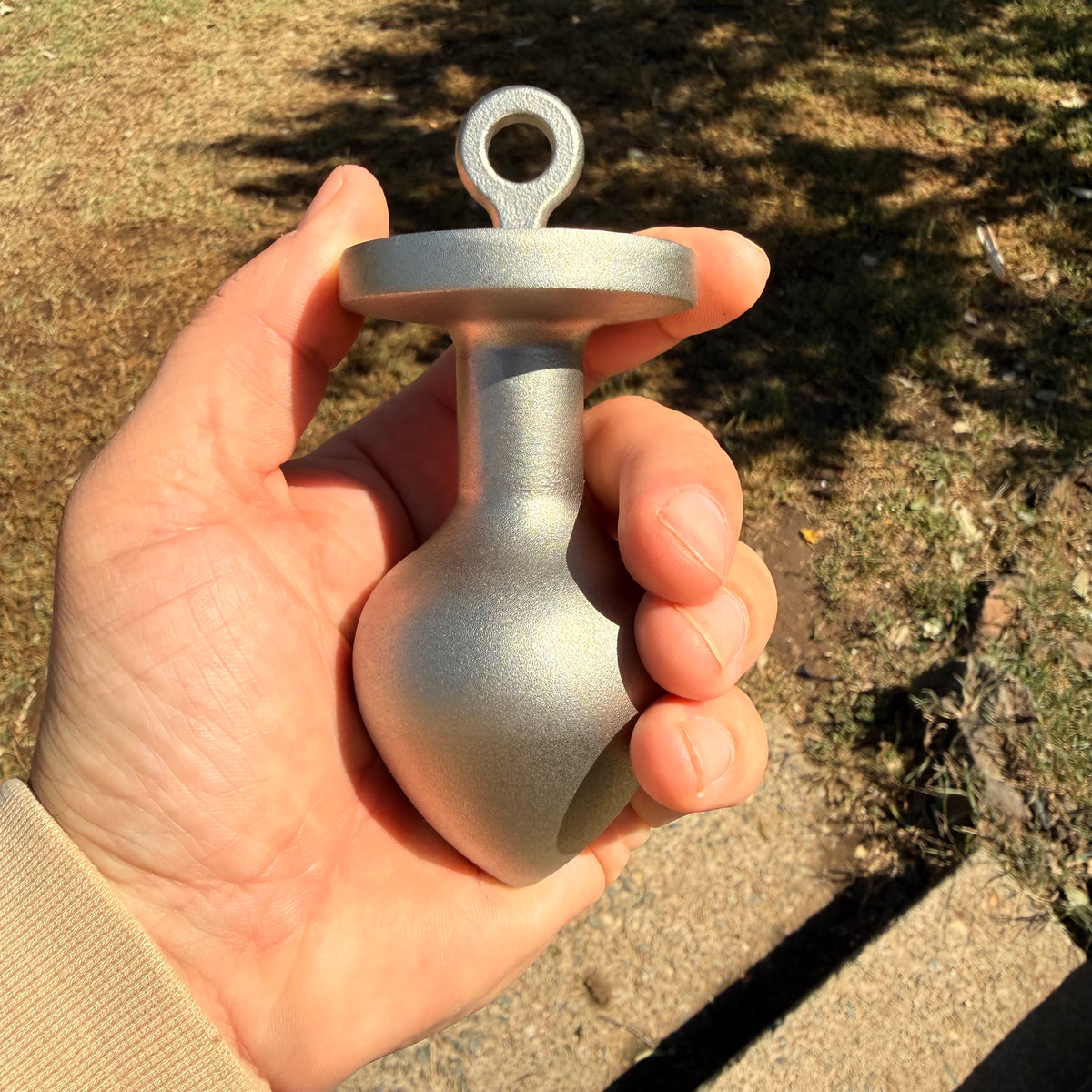 the plug plumb bob from tramp life industries. resembles a butt plug plumb bob. made from stainless steel 304. shown in a hand to see size