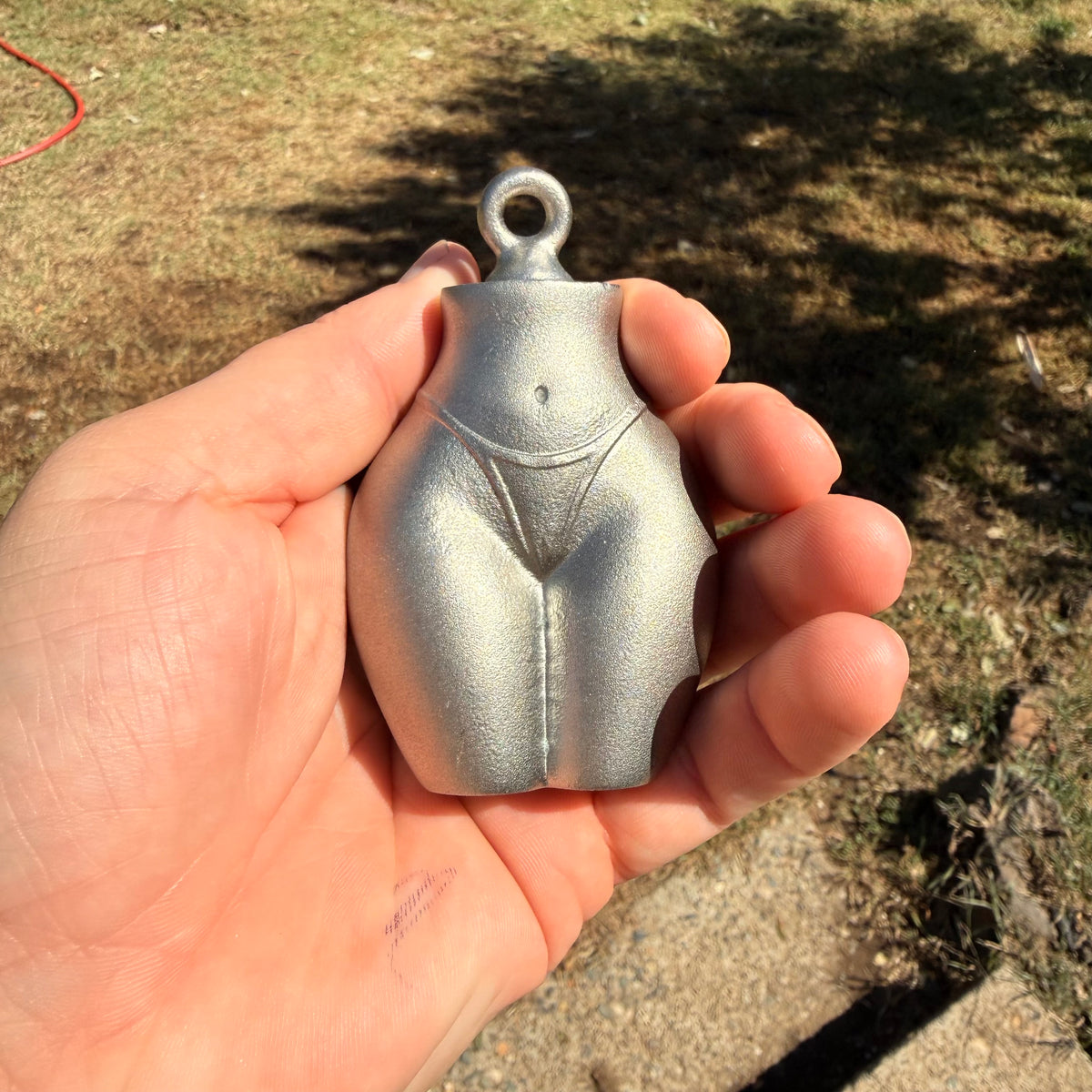 the bottom line plumb bob in a hand to showcase its size