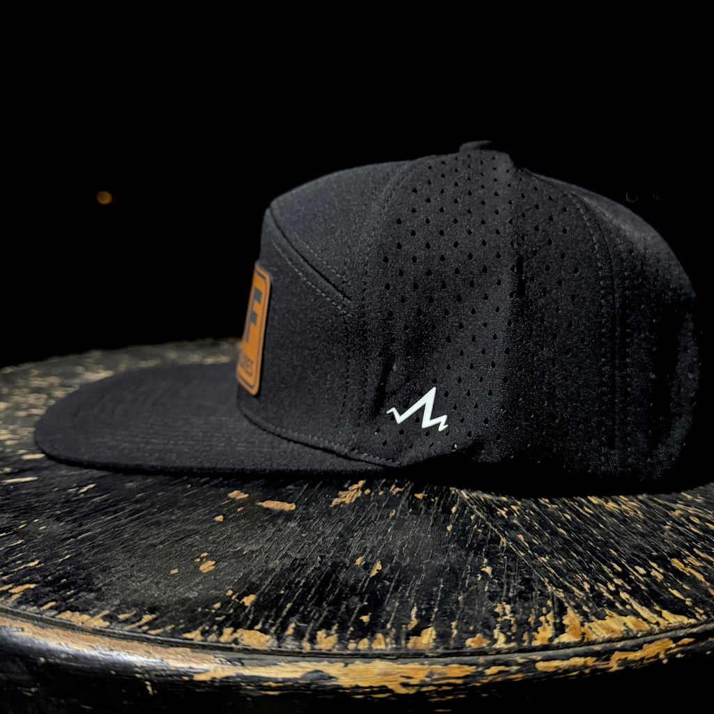 Black cap with a logo on a rustic wooden surface