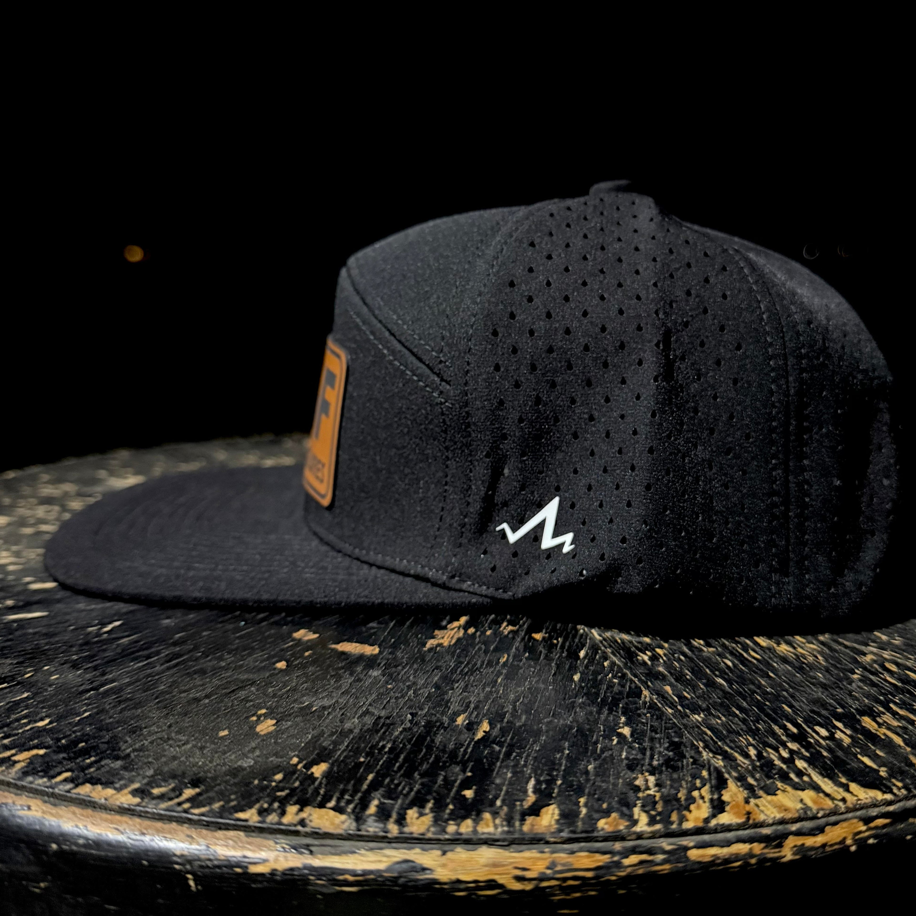 Black cap with a logo on a rustic wooden surface