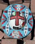 a turquoise sunshade with red, yellow, white and navy accents from tramp life industries on a white hard hat with tramp life stickers sitting on a pile of bricks