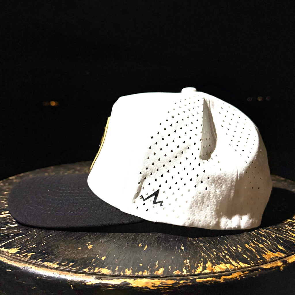 White baseball cap with black brim on a dark surface