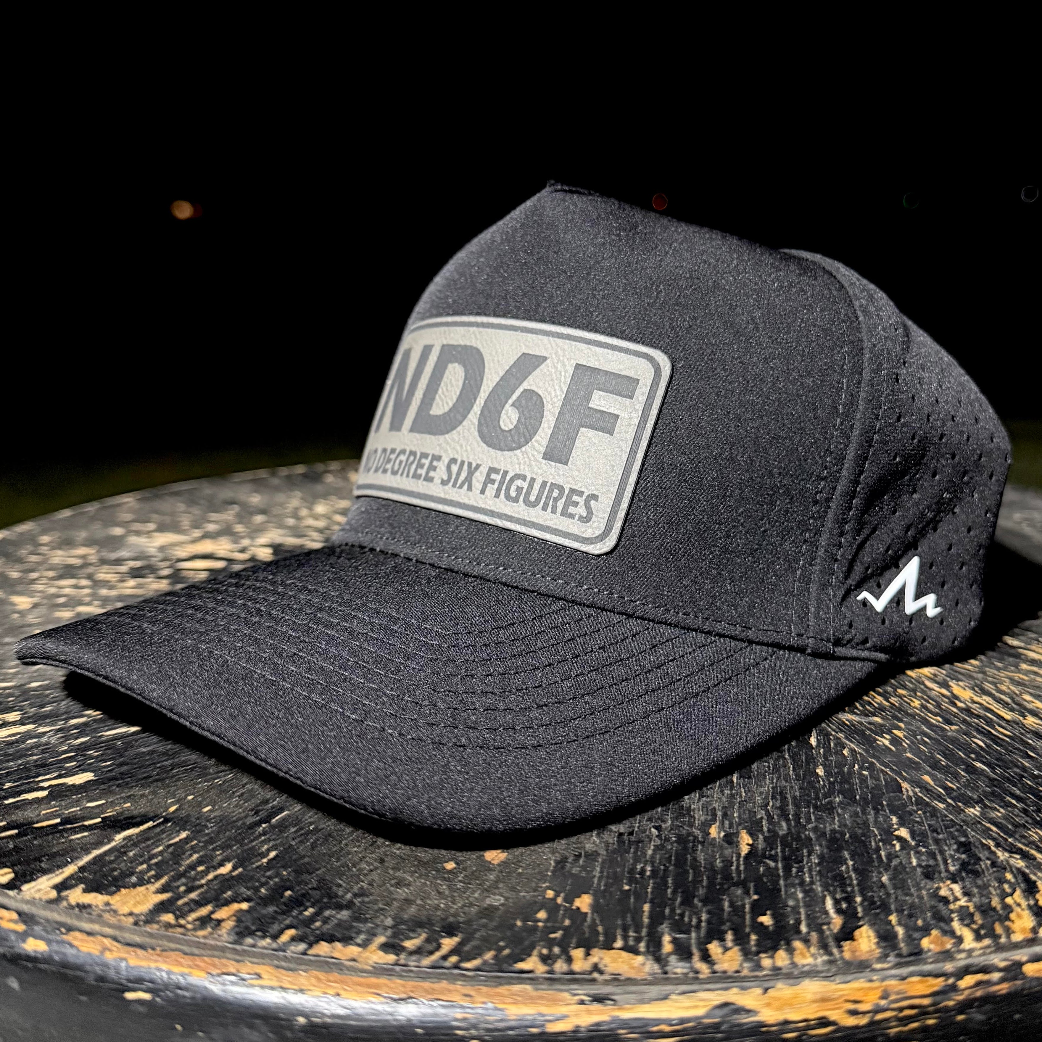 Black cap with a logo on a wooden surface