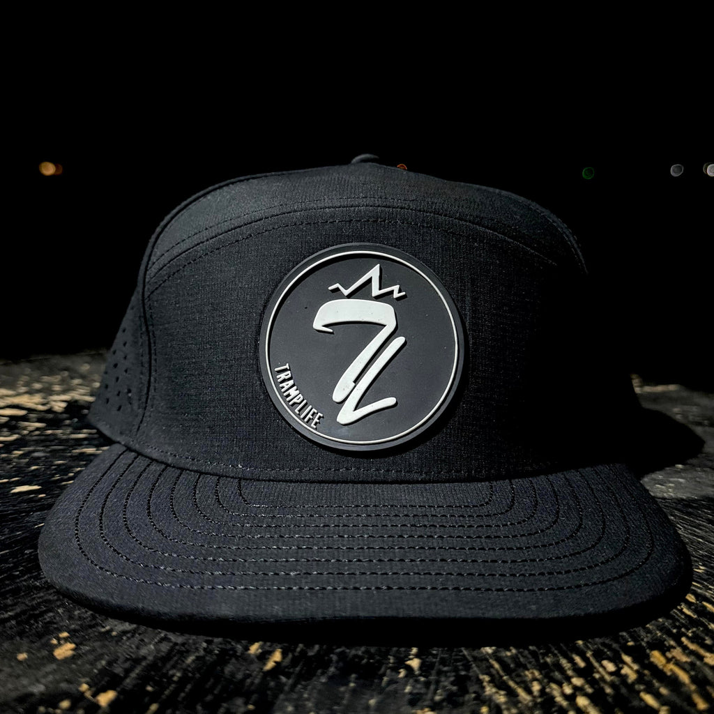 Black cap with a tramp life logo on a dark background