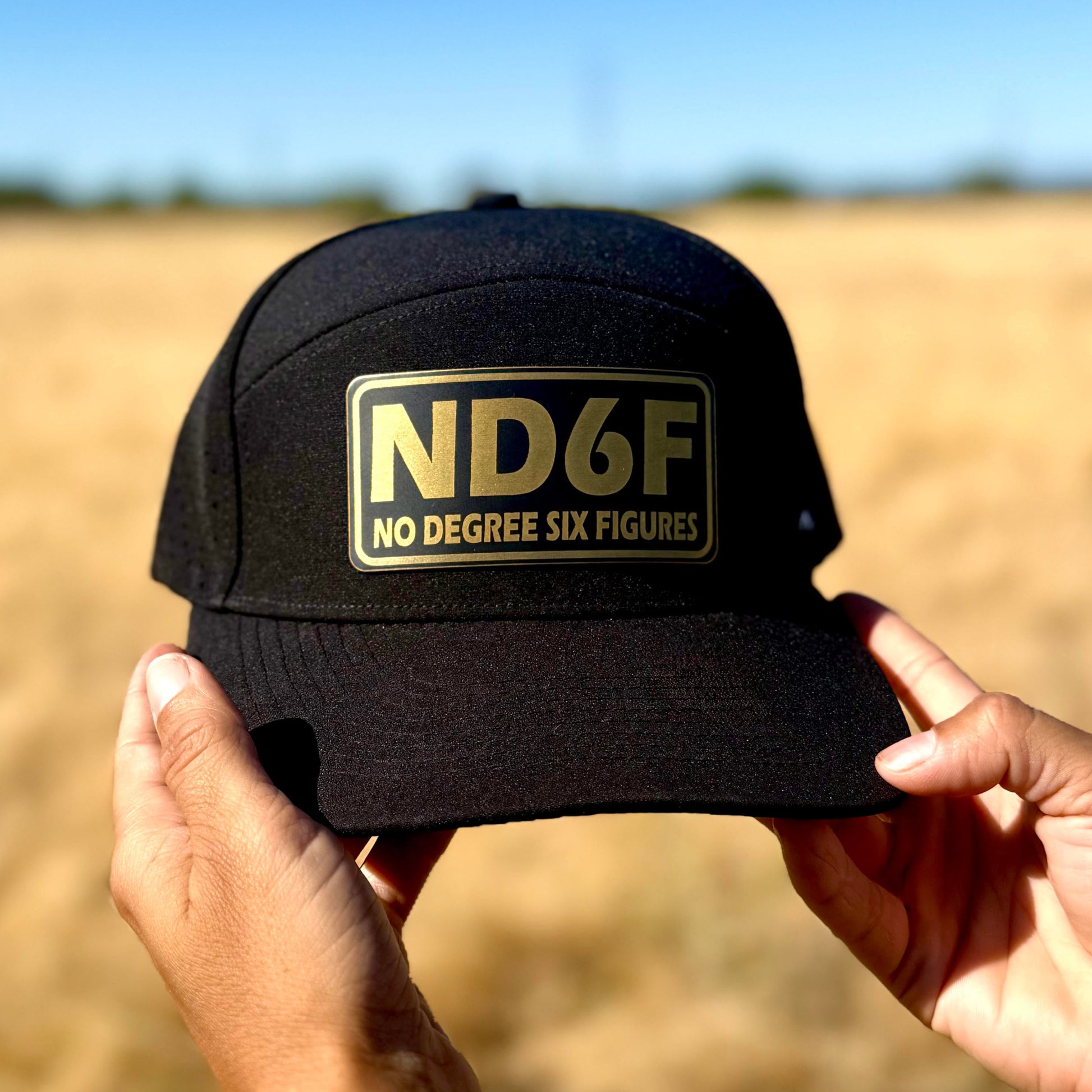 Black cap with 'ND6F' logo held in front of a field
