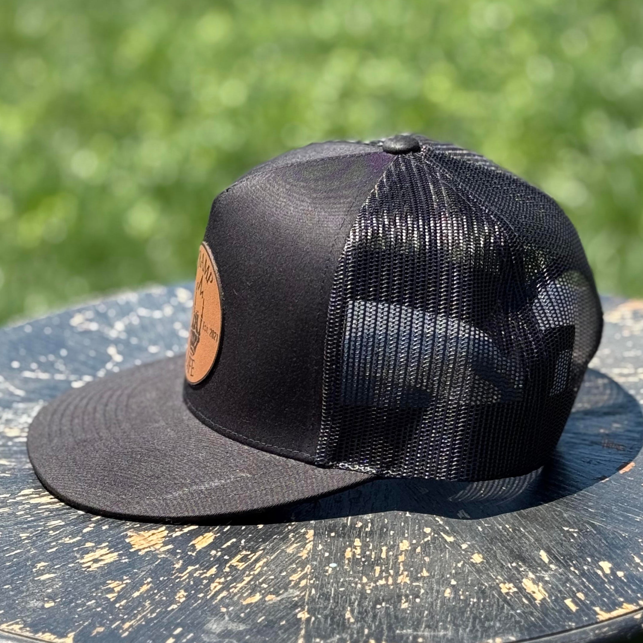 black yupoong snapback with a circular leather patch that has tramp life and a lightning bone hand on it