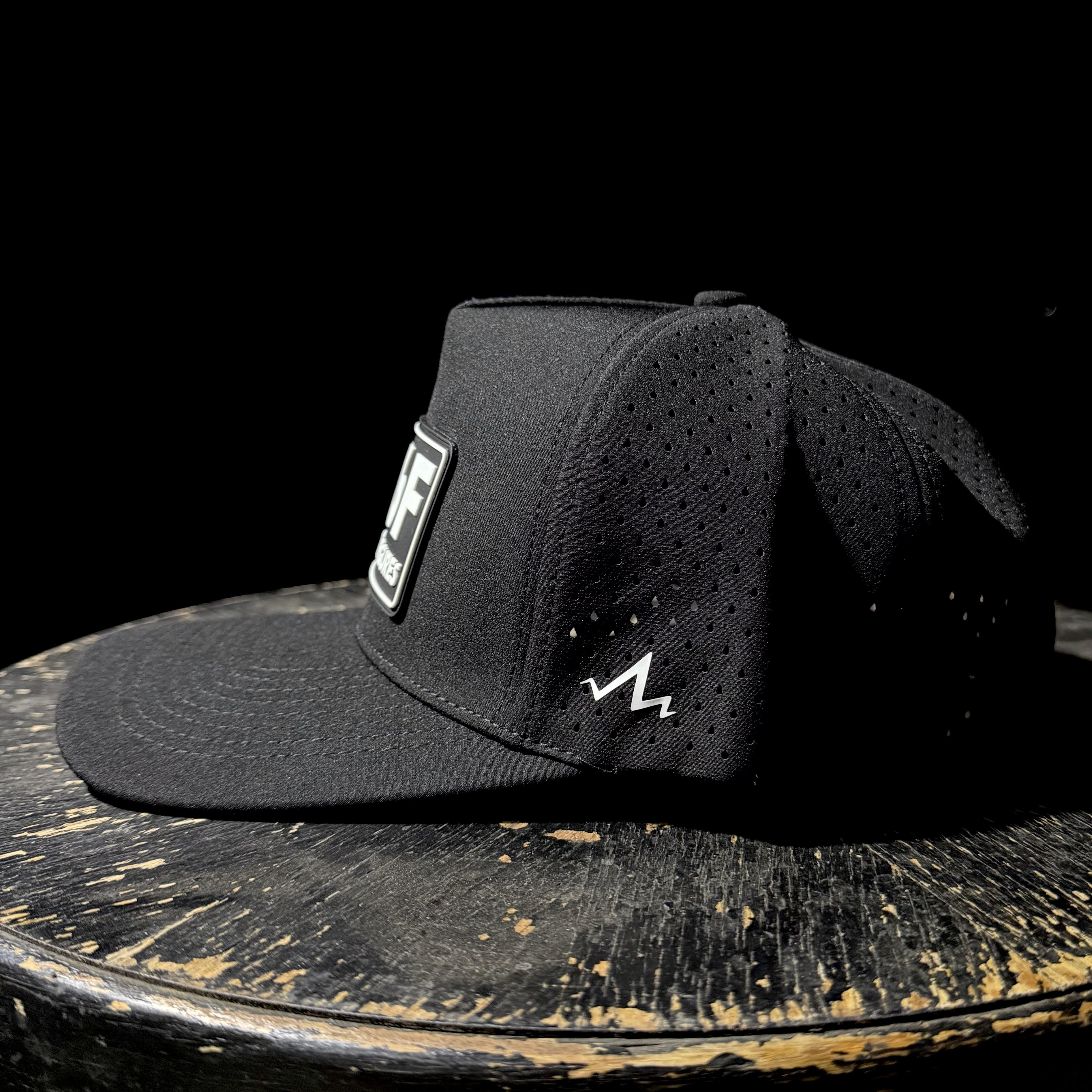 Black cap with a logo on a wooden surface against a black background