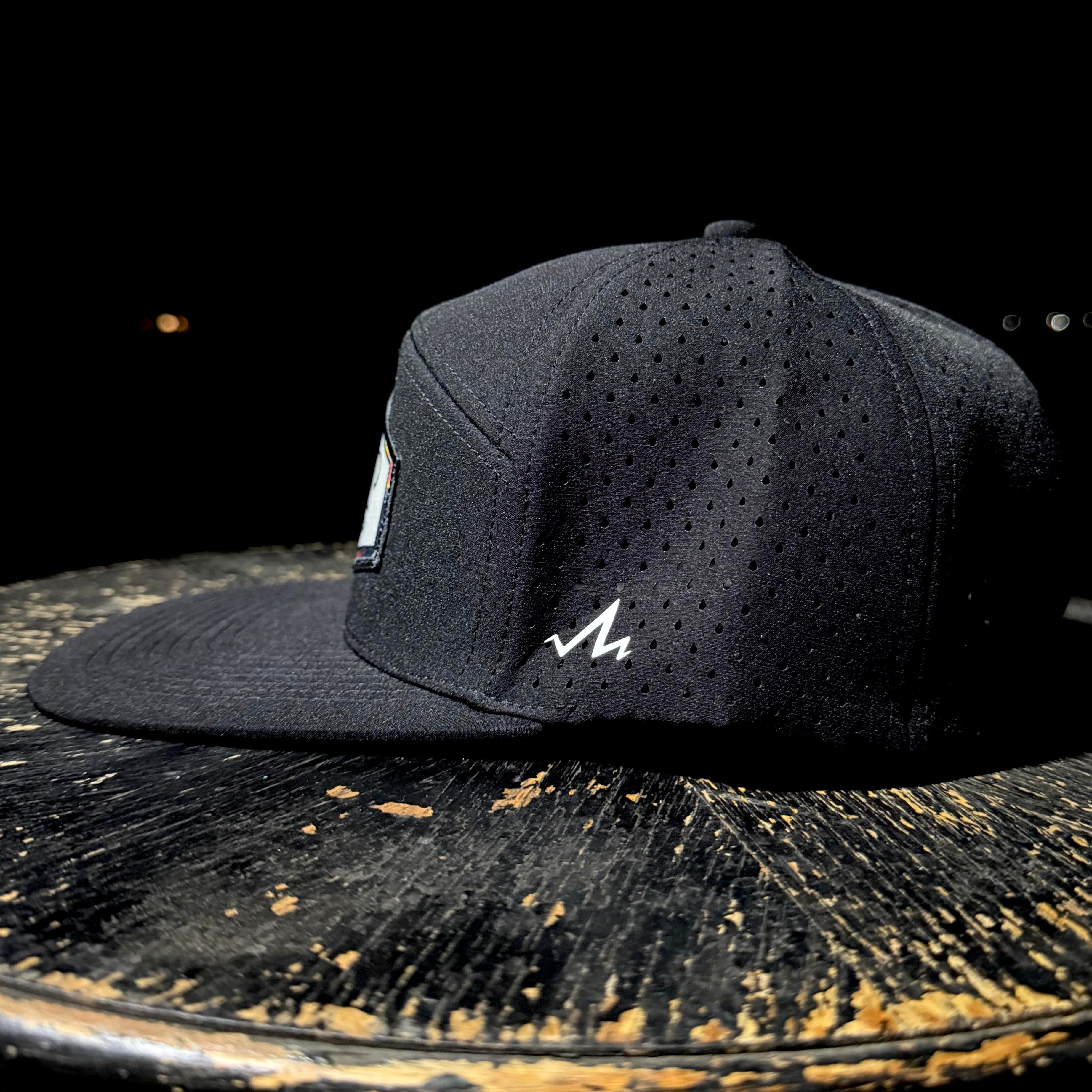 Black cap with a logo on a rustic wooden surface