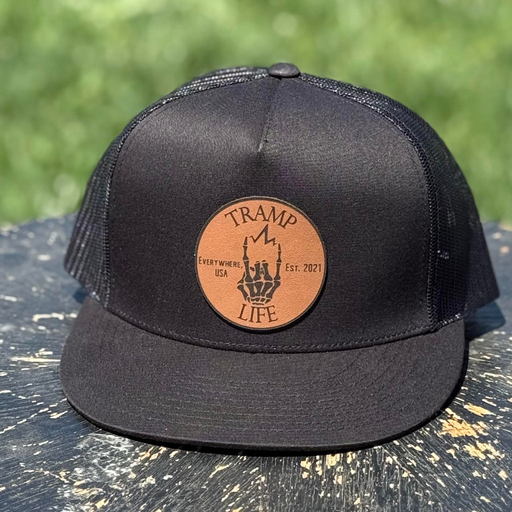 black yupoong snapback with a circular leather patch that has tramp life and a lightning bone hand on it