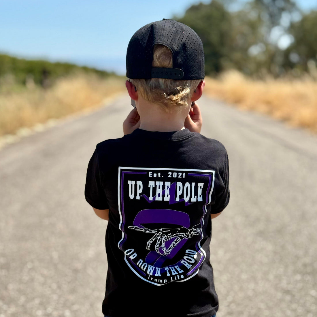 kid wearing a purple shirt from tramp life that says up the pole or down the road