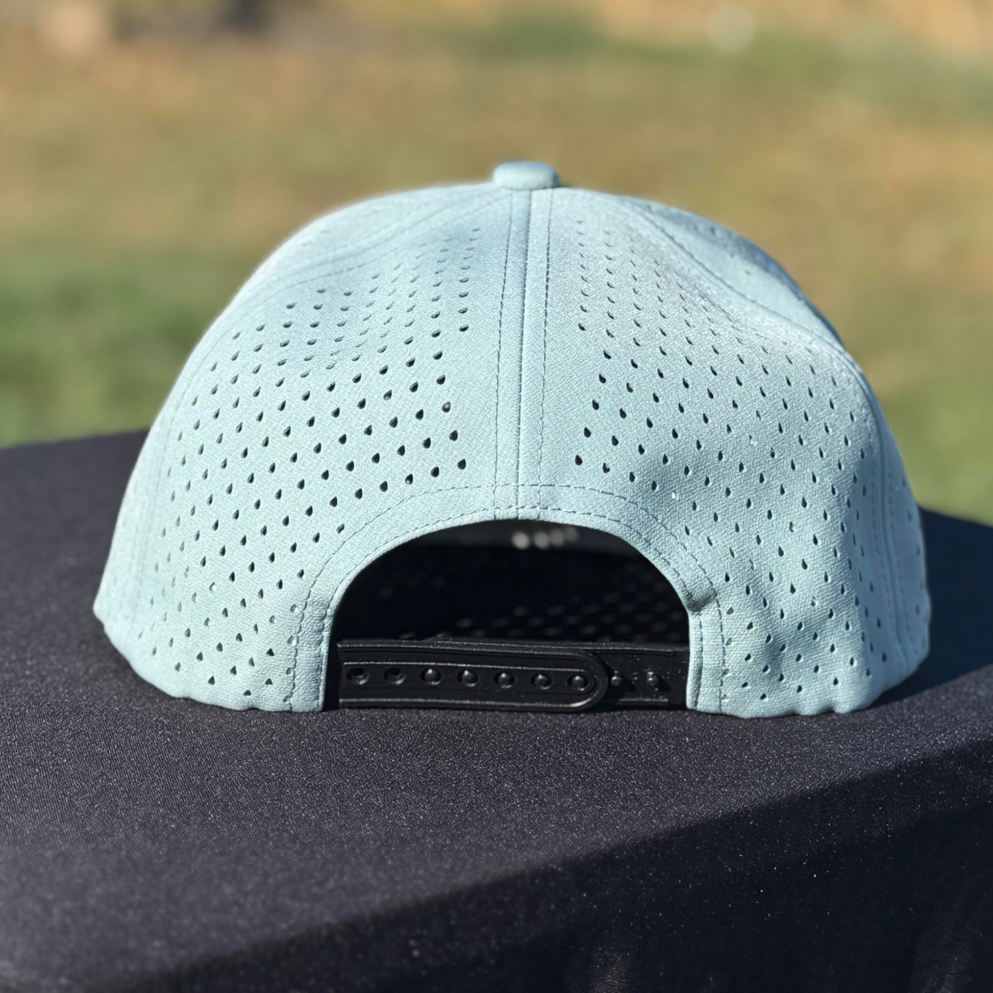 the back of a blue and black embroidered snapback water resistant hat with tramp life, a bone hand, make per diem great again for blue collar workers