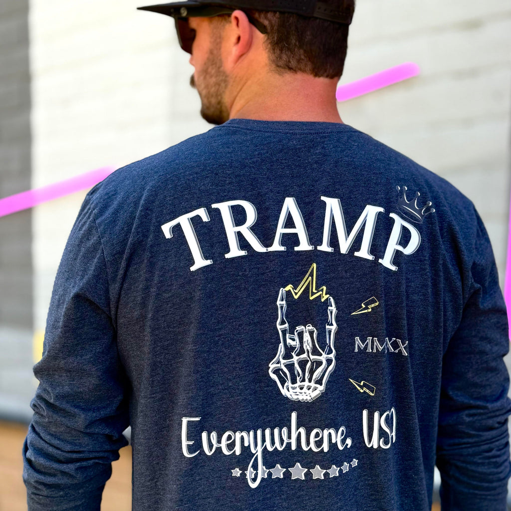 Person wearing a navy blue long-sleeve shirt with 'TRAMP' and 'Everywhere, US' text, standing in front of a gray wall with pink tape.