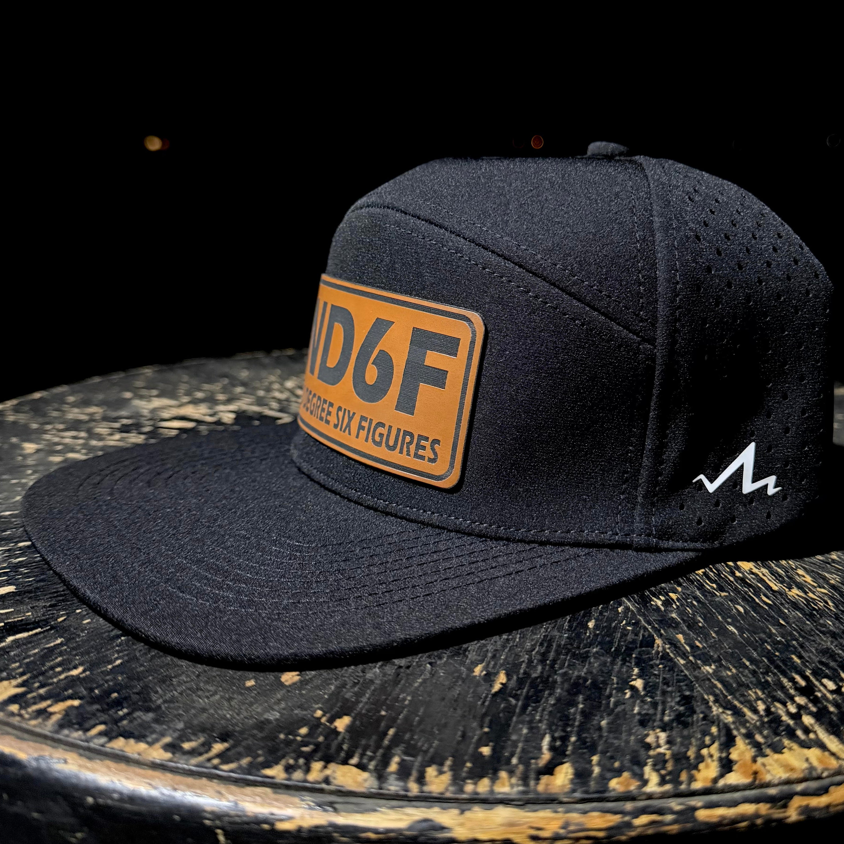 Black cap with a brown patch and logo on a dark surface