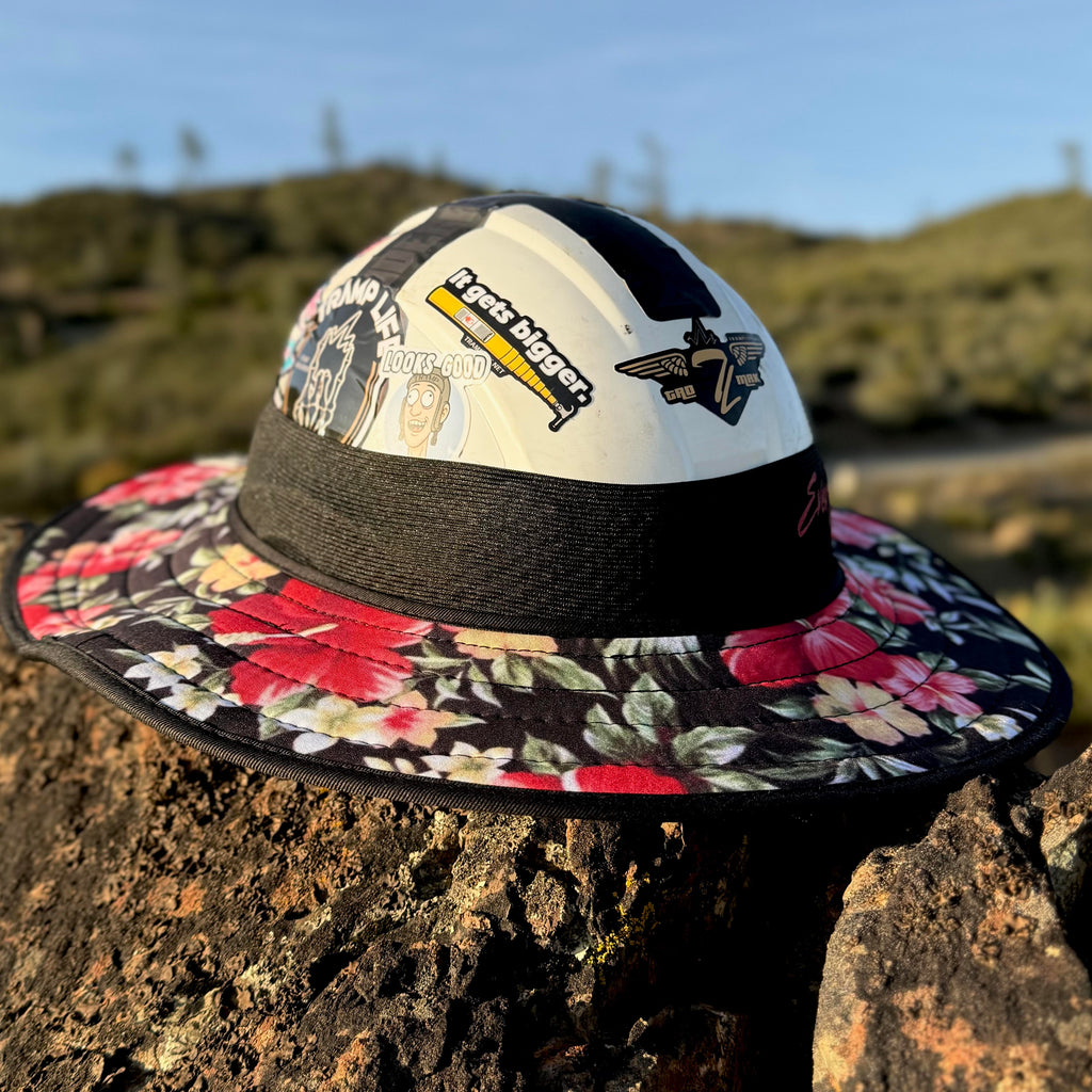 the aloha fly shade from tramp life industries, has pink hibiscus flowers on it. sitting on a rock